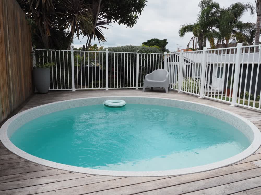 Circular tiled pool in fenced off, decked area